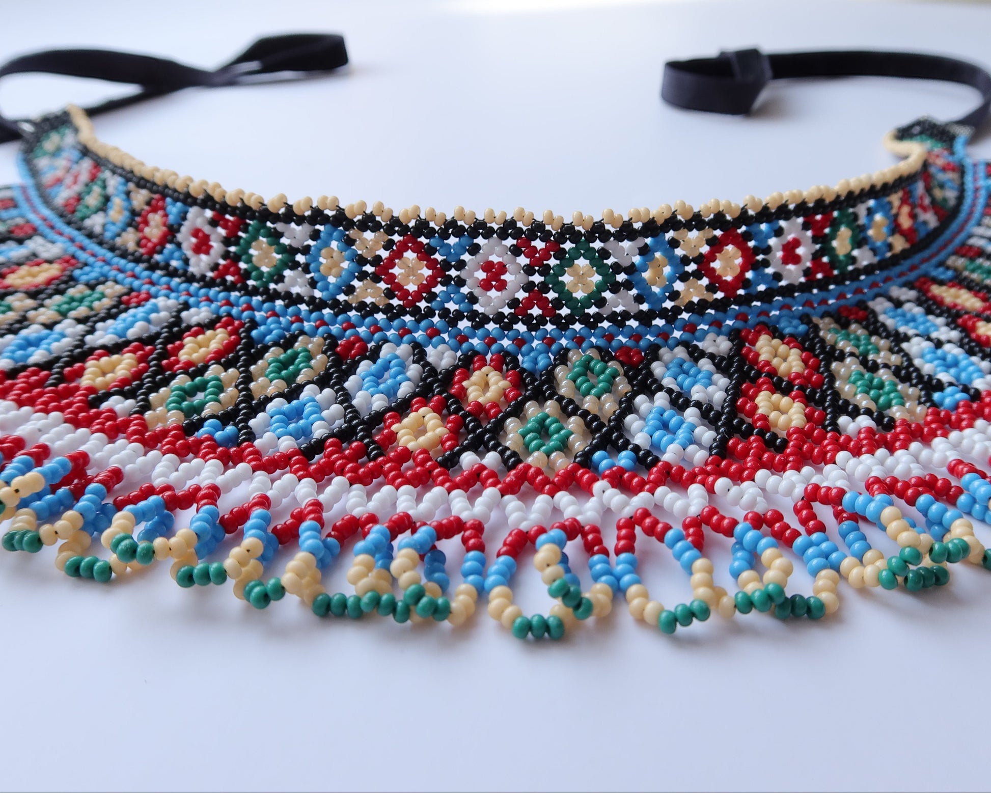 Comely UA two-part beaded necklace with red, black, blue, green, white, and cream Czech seed beads in a net-like structure with diamond motifs.