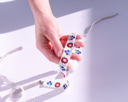Comely UA white beaded gerdan necklace with red, blue, and green floral motifs and velvet ribbon ties.