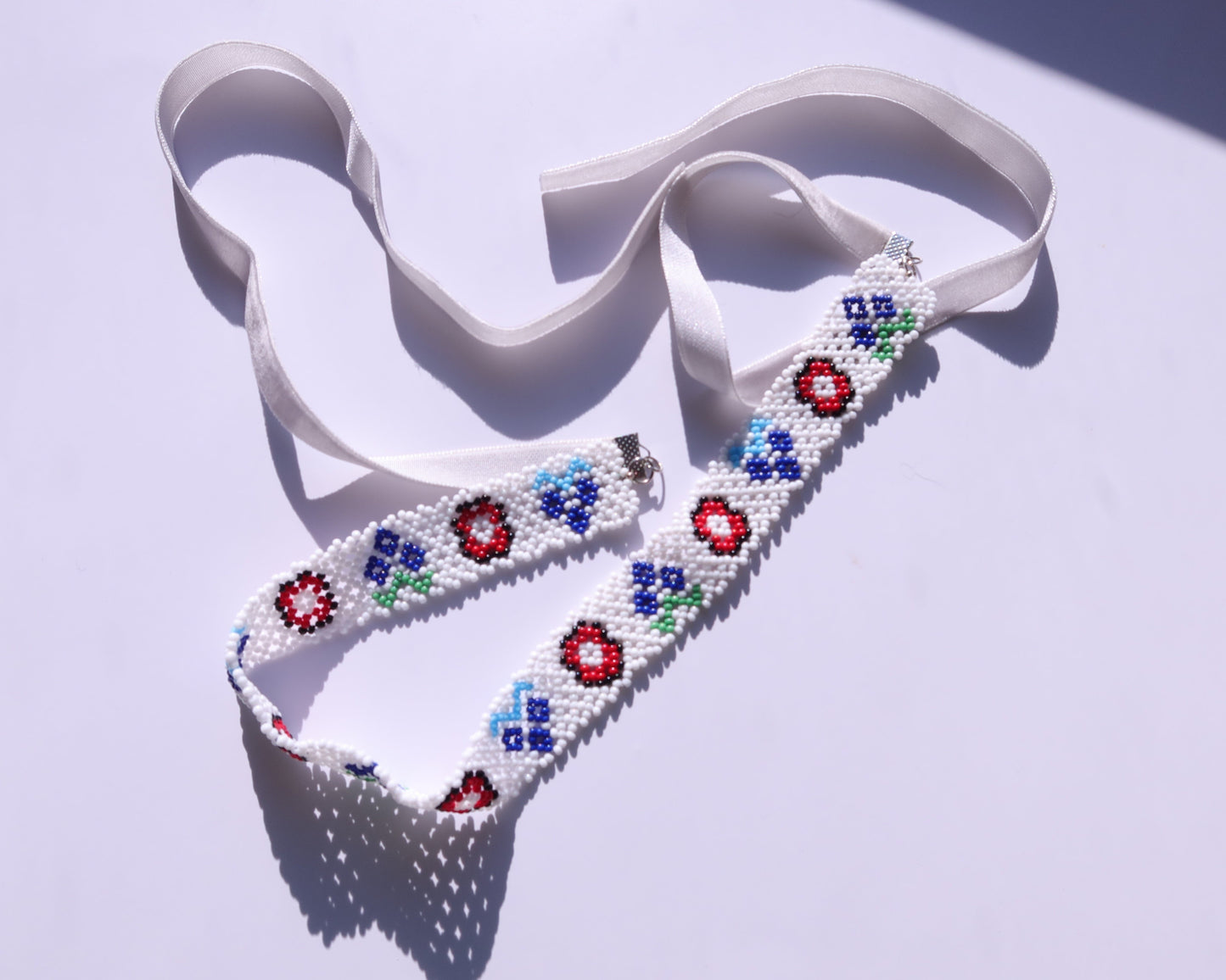 Comely UA white beaded gerdan necklace with red, blue, and green floral motifs and white velvet ribbons.