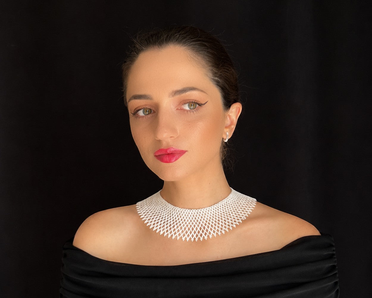 Comely UA white beaded silyanka necklace, a flat choker with a net-like pattern, worn by a woman against a black background.